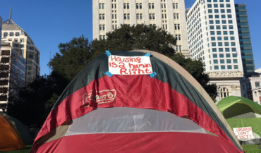 Tent in front of Oakland City Hall with message "Housing is a human right"
