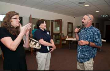 Linda Landers (left), a FEMA Disability Integrations Specialist, talks with John Russo (right) through a sign language interpreter after a meeting with local groups in Bastrop, TX in 2011. FEMA was working to provide wildfire assistance. Photo by Patsy Lynch/FEMA