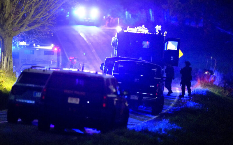 Law enforcement officers, right, stand near armored and tactical vehicles, center, near a property on Meadow Road, in Bowdoin, Maine, Thursday, Oct. 26, 2023. (AP Photo/Steven Senne)