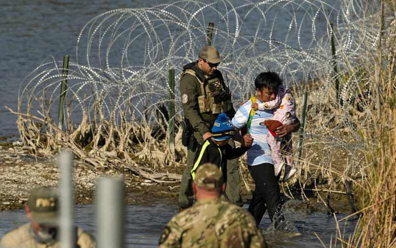 FILE - Migrants are taken into custody by officials at the Texas-Mexico border, Jan. 3, 2024, in Eagle Pass, Texas. The Supreme Court on Tuesday, March 12, 2024 extended a stay on a new Texas law that would empower police to arrest migrants suspected of illegally crossing the U.S.-Mexico border. The order puts the law on hold until at least Monday while the high court considers a challenge by the Justice Department, which has called the law an unconstitutional overreach. (AP Photo/Eric Gay, file)