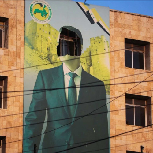 photo of a mural on the side of a multi-story building of Bashar Al-Assad with the face removed