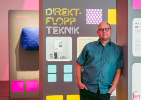 Samuel West is a white man. He is standing among his Museum of Failure exhibits.