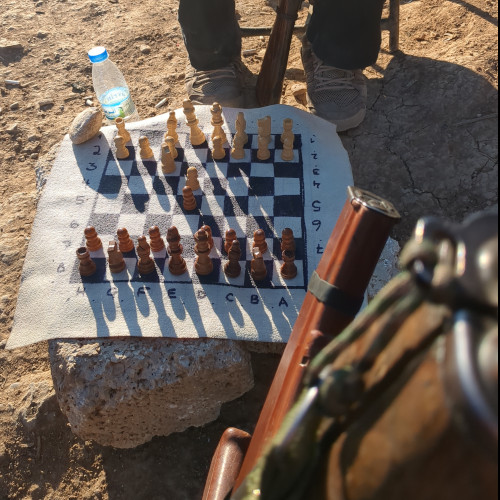a photo of two members of Tekosina Anarsist playing chess on the front lines