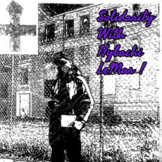 washed out black and white image of Hybachi in an adidas jumpsuit and mask holding lit in one hand, look at the camera from in front of a chainlink fence that divides foreground from a lawn and brick building in the bakcground. The image shows an anarchist black cross fist / cross, the words "Solidarity With Hybachi Lemar"