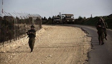 An Israeli army Bedouin tracker (L) examines the border fence between Israel and Lebanon during a border patrol, on March 12, 2013.
