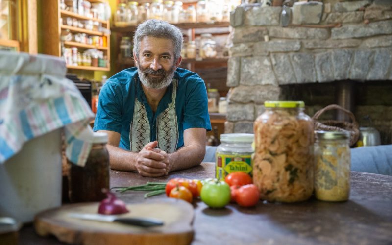 Sandor Katz surrounded by jars of fermented foods, vegetables in a kitchen