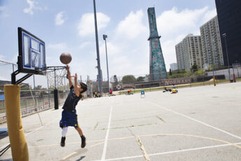 A boy plays basketball in front of an oil well that is covered with large colorful flowers and is located next to Beverly Hills High School. Wells like this are hidden throughout Los Angeles.Photo Credit: Sarah Craig/Faces of Fracking 