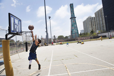 A boy plays basketball in front of an oil well that is covered with large colorful flowers and is located next to Beverly Hills High School. Wells like this are hidden throughout Los Angeles. Photo Credit: Sarah Craig/Faces of Fracking
