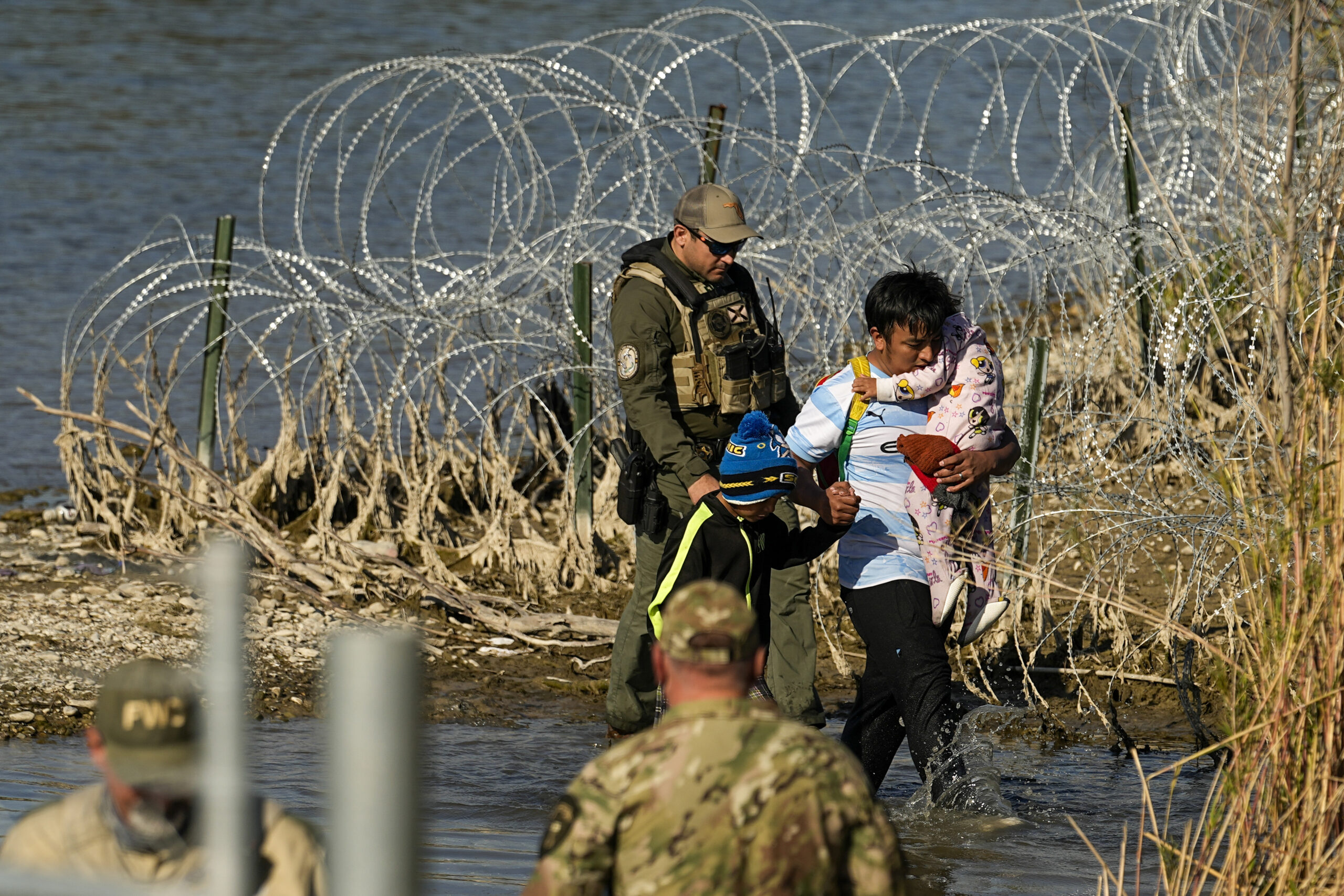 FILE - Migrants are taken into custody by officials at the Texas-Mexico border, Jan. 3, 2024, in Eagle Pass, Texas. The Supreme Court on Tuesday, March 12, 2024 extended a stay on a new Texas law that would empower police to arrest migrants suspected of illegally crossing the U.S.-Mexico border.  The order puts the law on hold until at least Monday while the high court considers a challenge by the Justice Department, which has called the law an unconstitutional overreach. (AP Photo/Eric Gay, file)