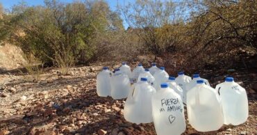 a photo water jugs left in the desert with kind notes scrawled on them